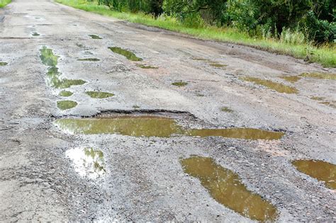 Premium Photo | Potholes on the road with stones on the asphalt The ...