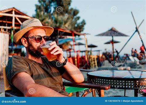 Cerveja Bebendo Do Homem Novo Em Uma Barra Da Praia Foto De Stock