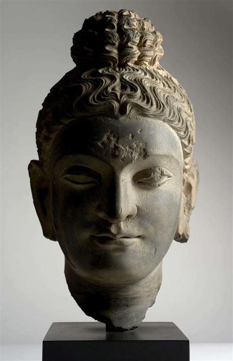 An Ancient Head Is Displayed On A Black Stand