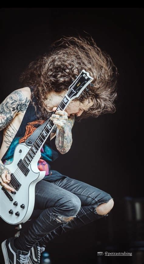 A Man With Long Hair Playing An Electric Guitar