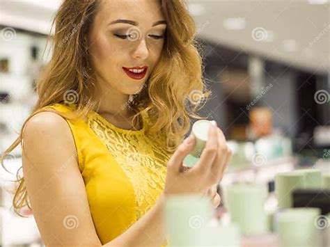 Young Attractive Smiling Girl In Yellow Dress Is Tasting Scent Of New