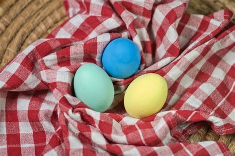 Tres huevos de pascua están en un paño a cuadros rojo y blanco Foto