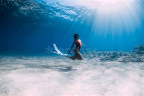 Woman Freediver In Red Swimsuit With White Fins Posing Underwater In