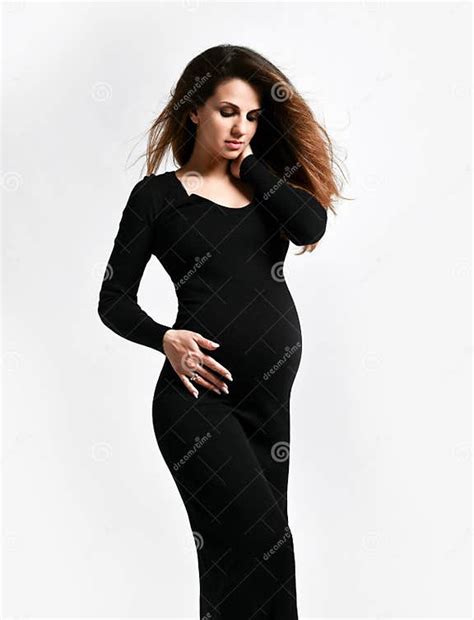 Brunette Pregnant Woman In Black Tight Dress She Put Hand On Her Belly While Posing Sideways