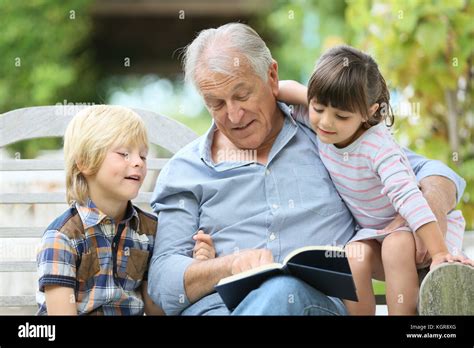 Senior Man Reading Book With Grandkids Stock Photo Alamy