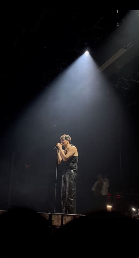 A Man Standing On Top Of A Stage Holding A Microphone In Front Of His Face