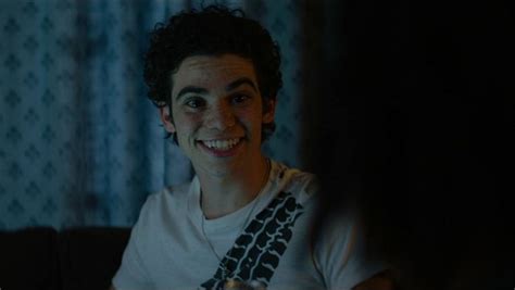 a young man is smiling while sitting in the dark