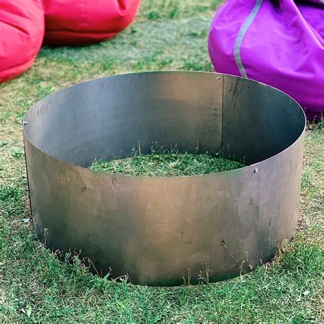 a large metal bowl sitting on top of a lush green field next to purple bags