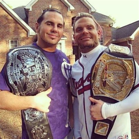 Two Men Standing Next To Each Other In Front Of A House Holding Up