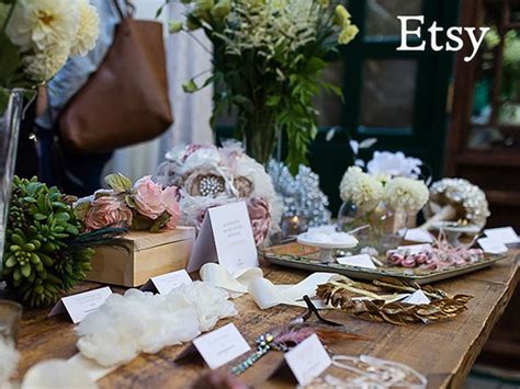 The Table Is Covered With Flowers And Other Items For Sale At An