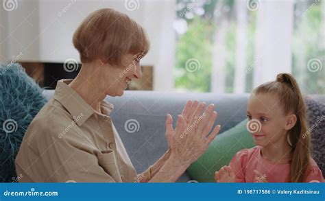 Happy Grandmother And Granddaughter Playing Patty Cake At Home Stock