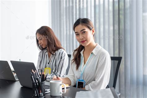 Two Asian Female Accountant Sitting Working Together In The Office