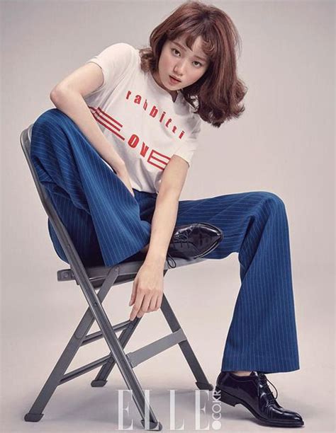 A Woman Sitting On Top Of A Chair Wearing Blue Pants And A White T Shirt