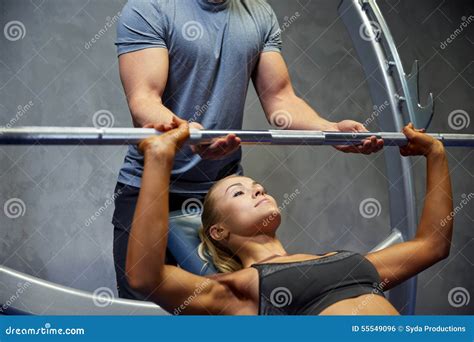 Hombre Y Mujer Con El Barbell Que Dobla Los Músculos En Gimnasio Foto