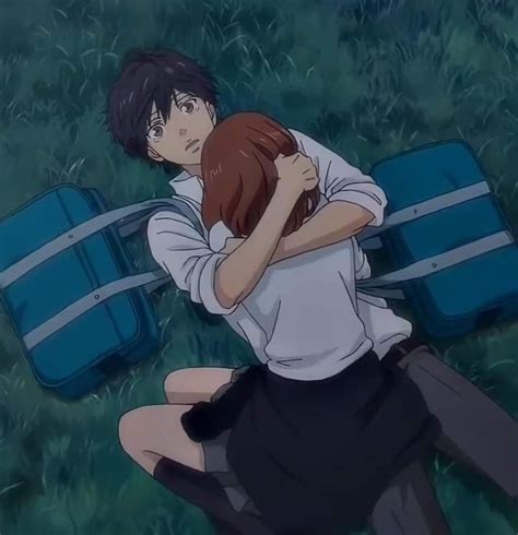 A Man And Woman Hugging Each Other In The Grass With Suitcases On Their