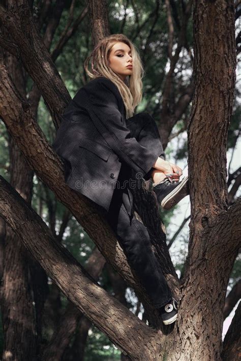 Young Woman Dressed In All Black Sits In A Tree During The Daytime