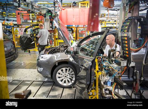 Car Assembly Workers Fitting Doors To Cars On Production Line In Car