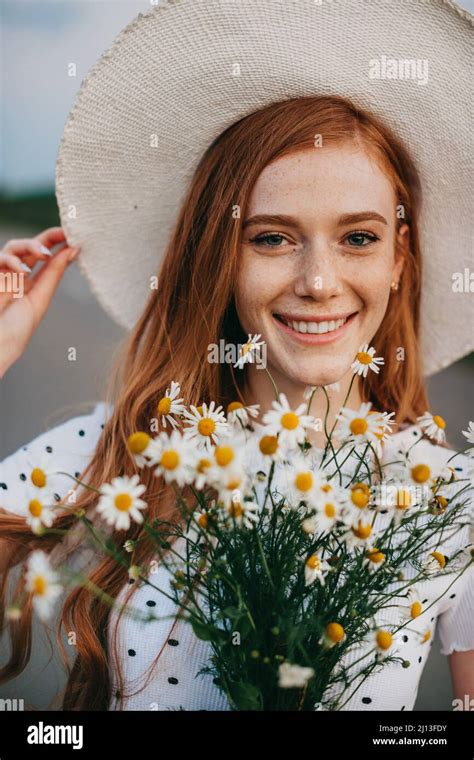 Portrait Of A Woman With Red Hair Holding A Bouquet Of Daisies Wearing