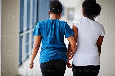 Back Of Two African Woman Friends In T Shirts Walking Halding Hands