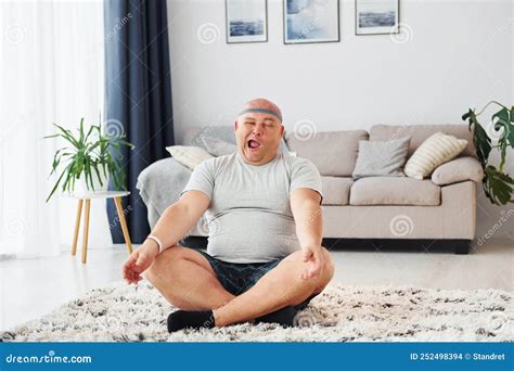 Doing Yoga Exercises Funny Overweight Man In Casual Clothes Is Indoors