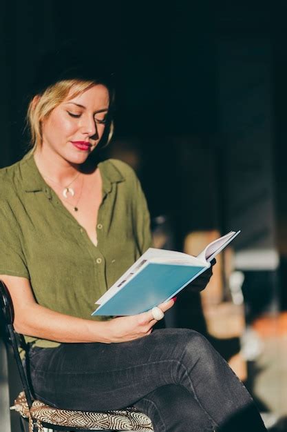 Jeune Femme Assise Sur Une Chaise Avec Un Livre Photo Gratuite