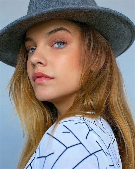 A Woman Wearing A Gray Hat With Long Blonde Hair And Blue Eyes Looks