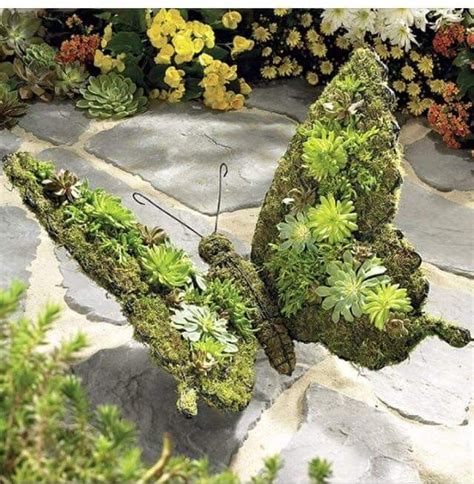 Two Moss Covered Butterfly Sculptures Sitting On Top Of A Stone Walkway