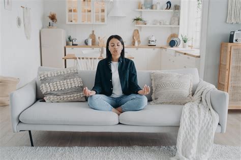 Mujer practicar yoga relajarse respirar sentado en el sofá en casa