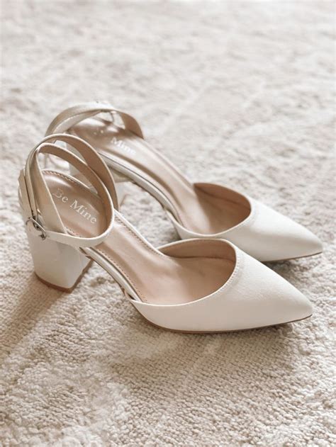 A Pair Of White High Heeled Shoes Sitting On Top Of A Carpet Covered Floor