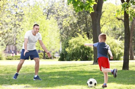 Padre E Hijo Jugando Al F Tbol En La Hierba Verde En El Parque Foto