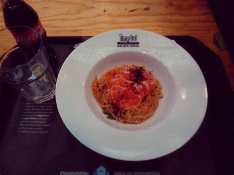 A White Plate Topped With Pasta And Shrimp Next To A Bottle Of Soda On