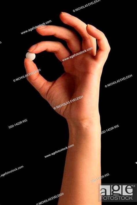 Person S Hand Holding A White Pill Between The Fingers Stock Photo