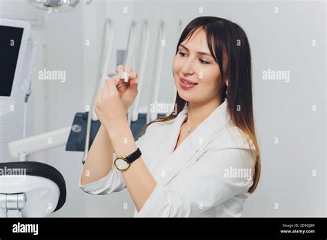 Portrait Of Attractive Smiling Female Dentist With Hands Folded Stock