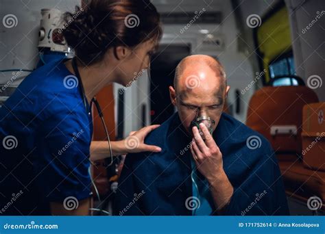 Nurse In Medical Uniform Puts Her Hand On Man Who Sits In Oxygen Mask