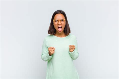 Mujer latina gritando agresivamente con mirada molesta frustrada enojada y puños apretados