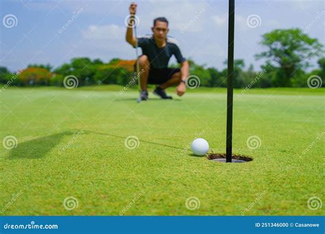 Golfer Putt Golf Ball Into Hole On The Green At Golf Course Stock Photo