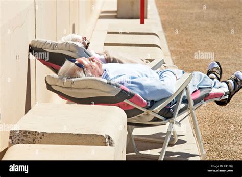 Senior Couple Sleeping On Deck Chairs In The Summer Sunshine Stock