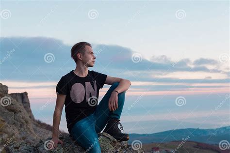 Young Attractive Man Located With On The Top Of Mountains Against The