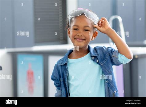 Portrait d une écolière biraciale souriante qui élève des lunettes de