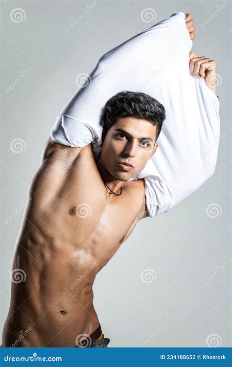 Man Posing Shirtless Taking Off His White T Shirt Looking At Camera