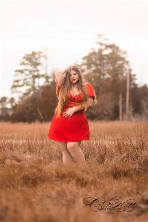 A Woman In A Red Dress Standing In A Field