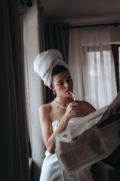 Mulher Jovem E Bonita Em Uma Toalha Fuma Um Cigarro E L Jornal Foto