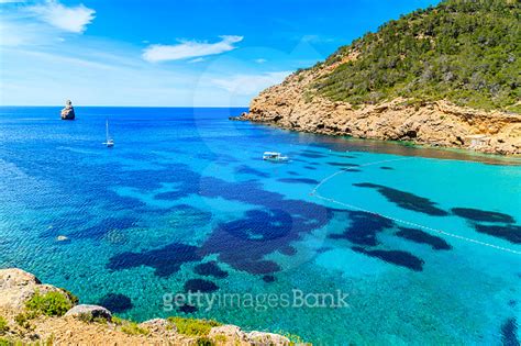 View Of Cala Benirras Bay With Fishing Boat On Azure Blue Sea Water