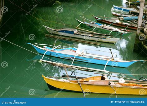 Traditional Filipino Fishing Boats Stand In The Bay Near The Coast