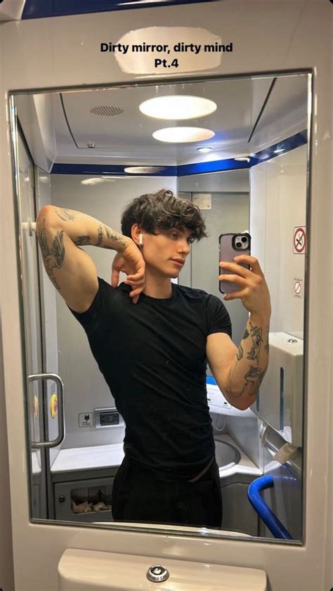 A Man Taking A Selfie In Front Of A Mirror With Tattoos On His Arm