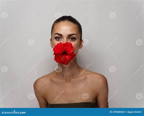 Pretty Woman With Red Flower In Her Mouth Naked Shoulders Cosmetics Light Background Stock Photo