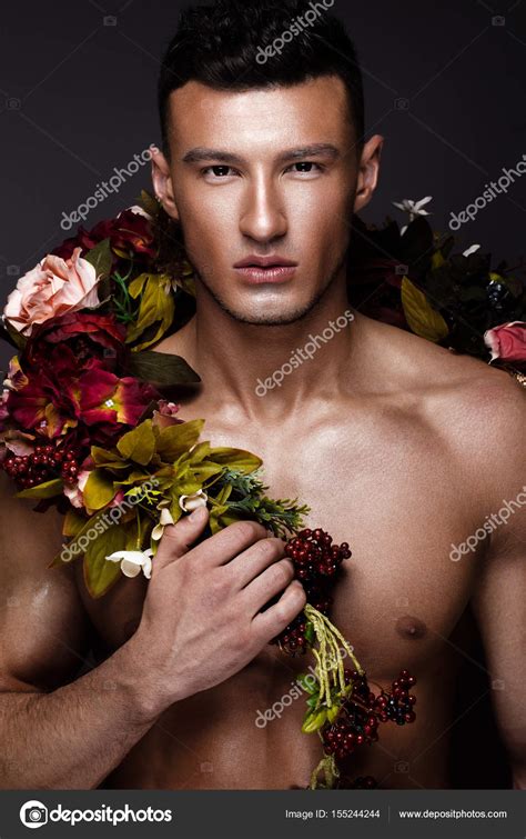 Un Hombre Guapo Con Un Torso Desnudo Bronceado De Bronce Y Flores En