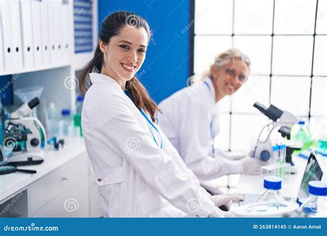 Two Women Scientists Using Microscope Working At Laboratory Stock Image