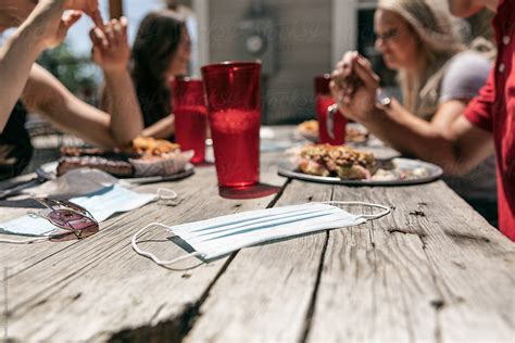 Bbq Focus On Face Mask On Table While Friends Eat By Stocksy