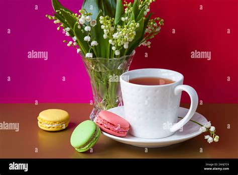 French Multicolored Cakes Macarons And A Cup Of Tea A Bouquet Of Lily